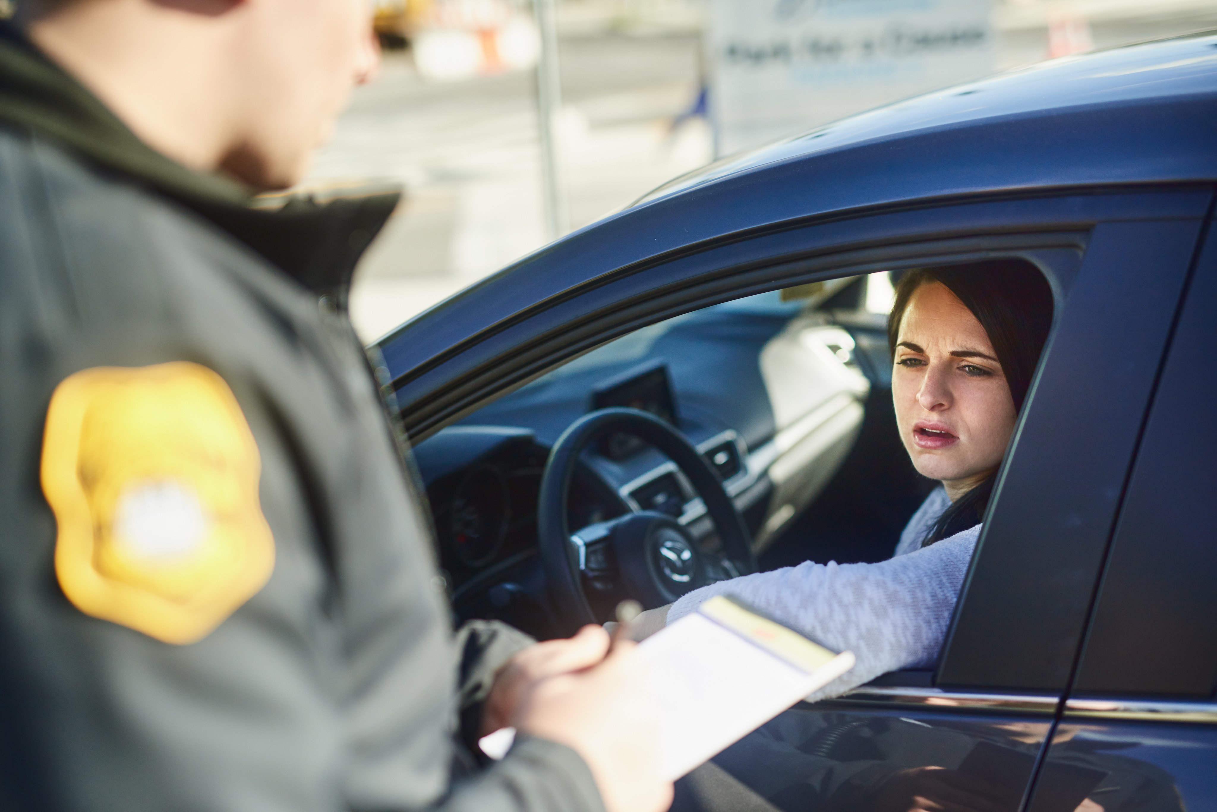 Cropped shot of an unrecognizable male traffic officer issuing a ticket to a female civilian at a roadblock