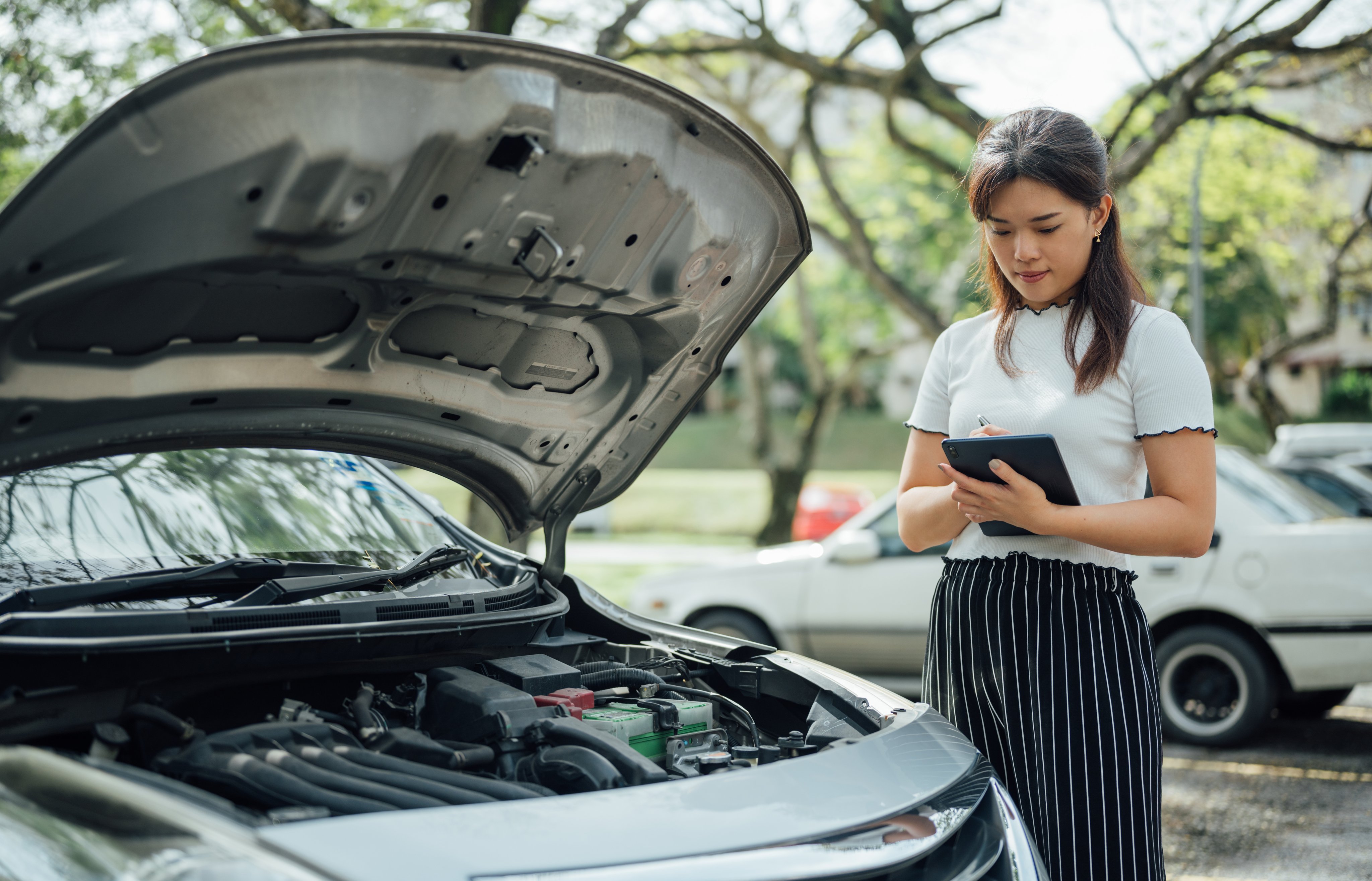 Automobile insurance adjuster using digital tablet to inspecting damage to vehicle.