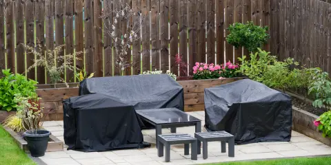 Backyard patio with outdoor furniture and grill covered in black waterproof covers