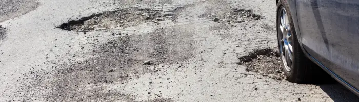 Car and cracked asphalt with holes