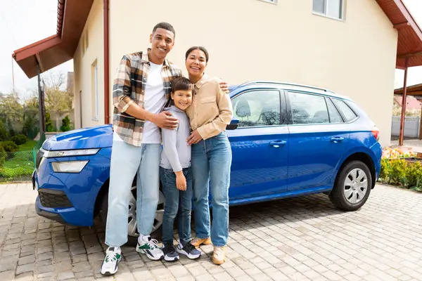 Happy family with their son arrived by car to their new home, posing and embracing