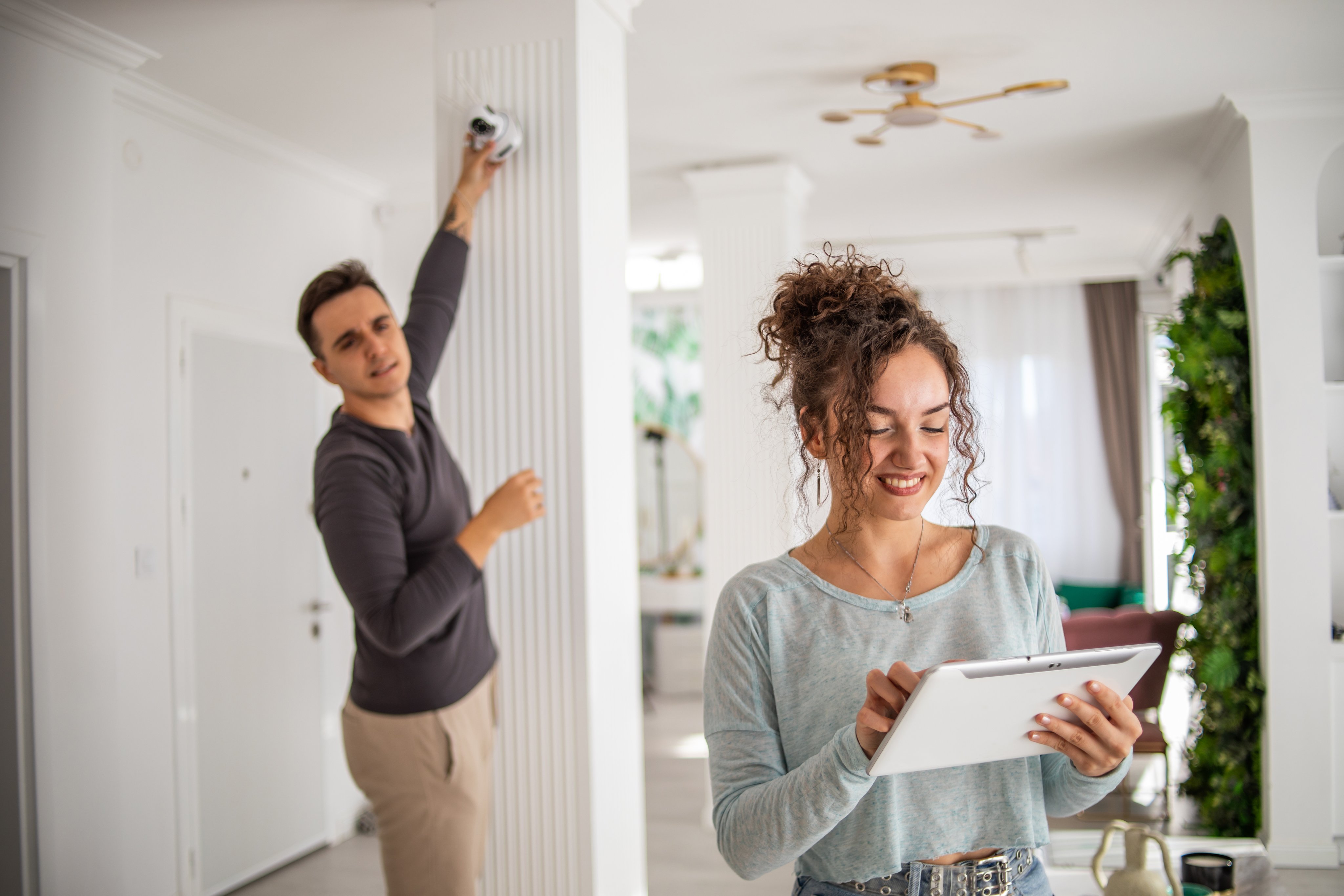 A young couple installs a security camera in their new home