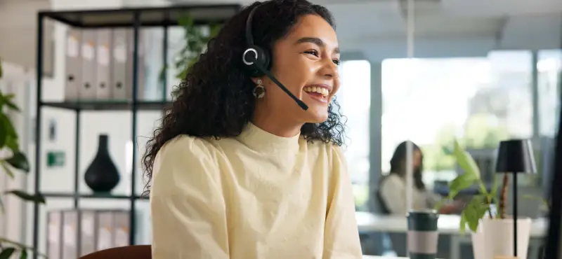 Laughing, happy woman and customer service in call center with agent, communication and online consulting