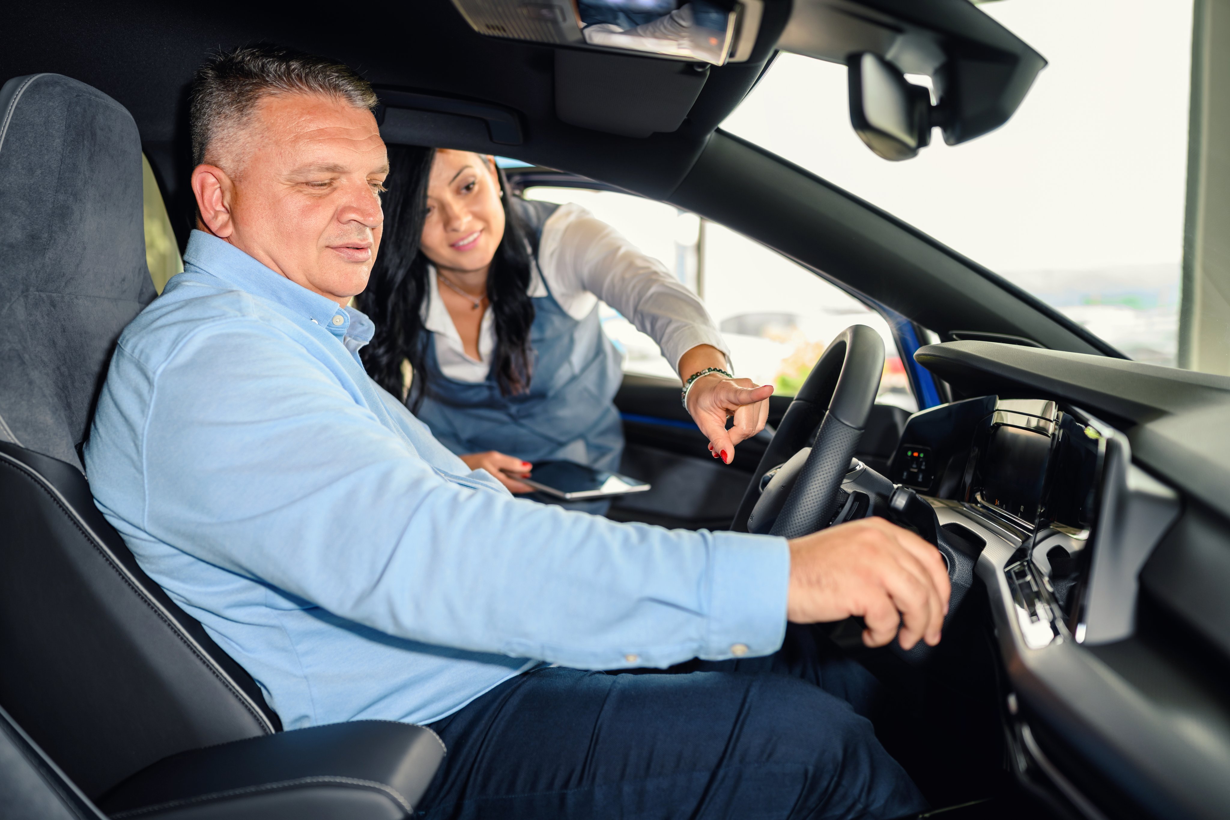 Saleswoman helping the male customer to choose a new car