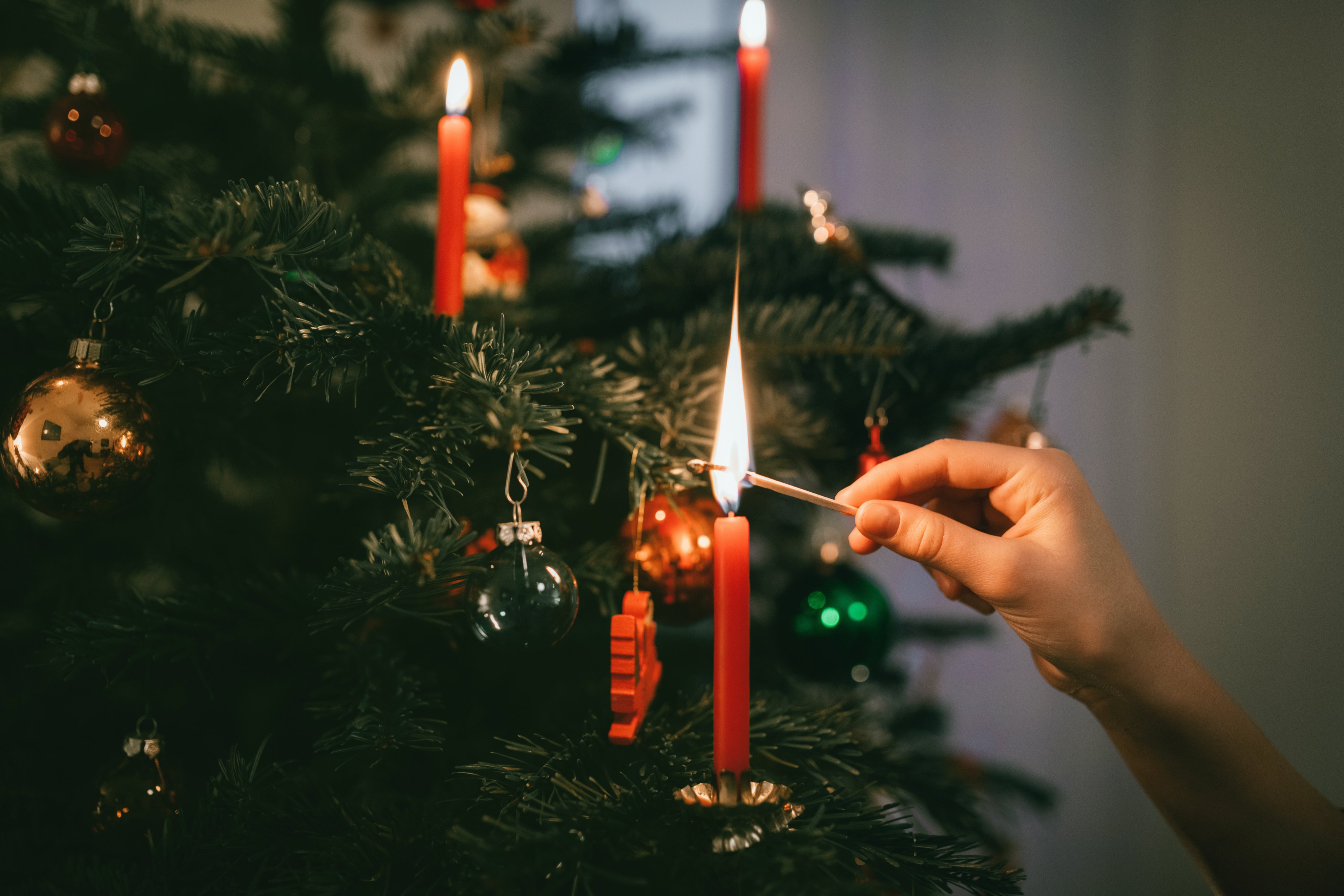 Hand lighting candle on a christmas tree