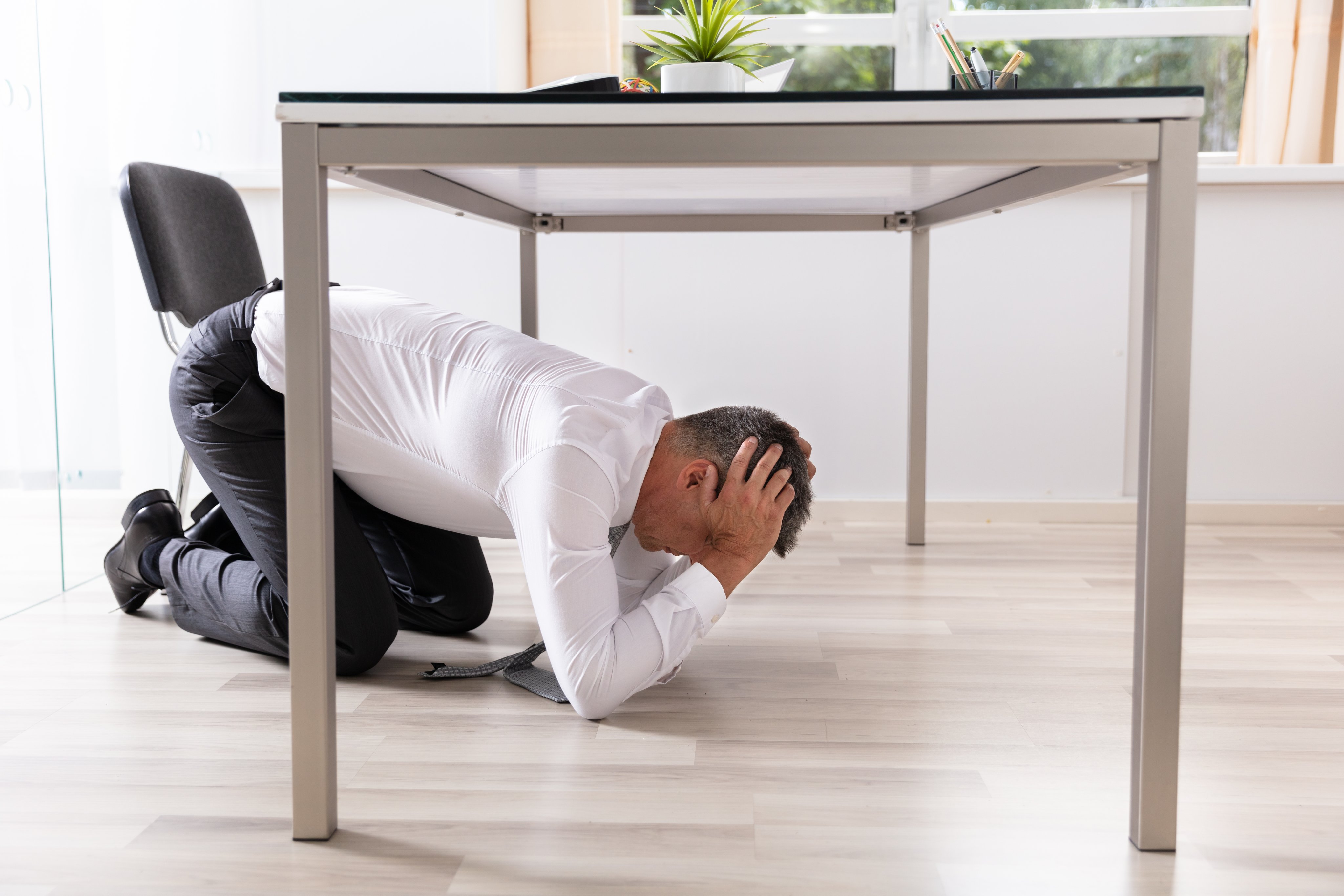 Man taking cover under table