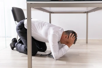 Man taking cover under table