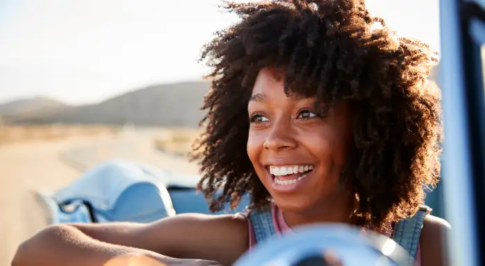 Portrait of woman enjoying road trip in open top classic car