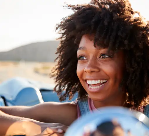 Portrait of woman enjoying road trip in open top classic car