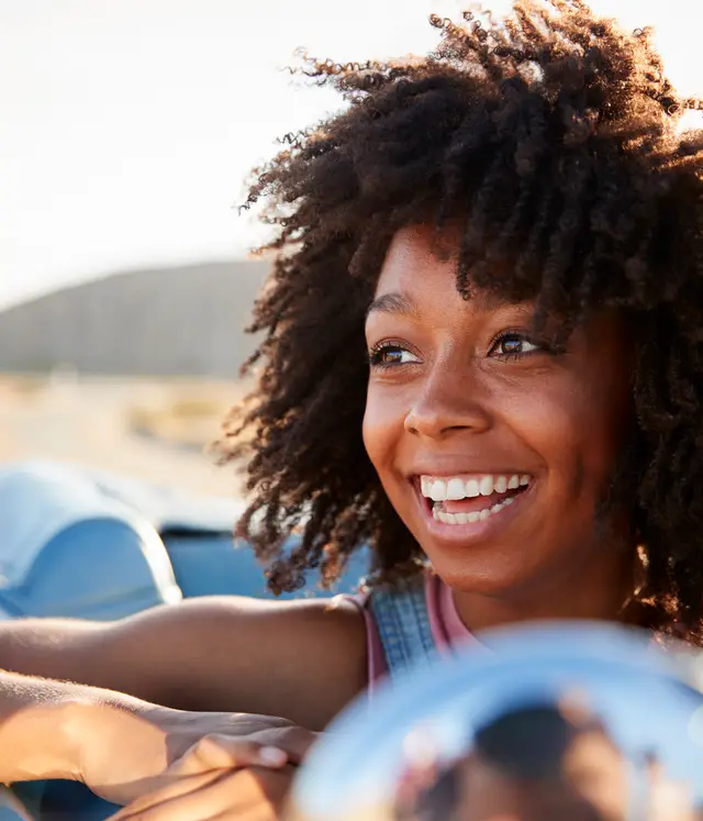 Portrait of woman enjoying road trip in open top classic car
