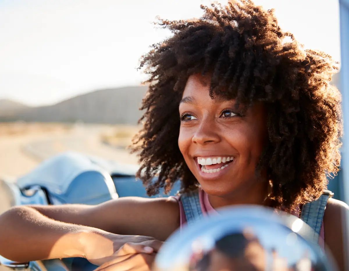 Portrait of woman enjoying road trip in open top classic car