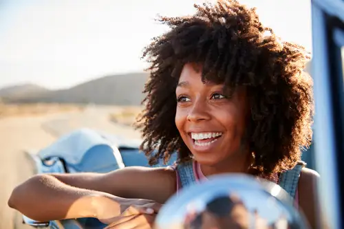 Portrait of woman enjoying road trip in open top classic car