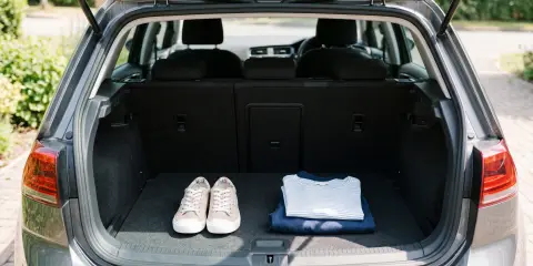 Open car trunk with a neatly placed pair of shoes and folded clothes inside