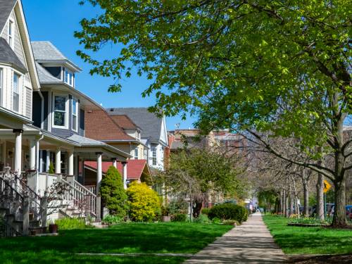 A row of old wooden homes with front lawns and a sidewalk in the North Center neighborhood of Chicago