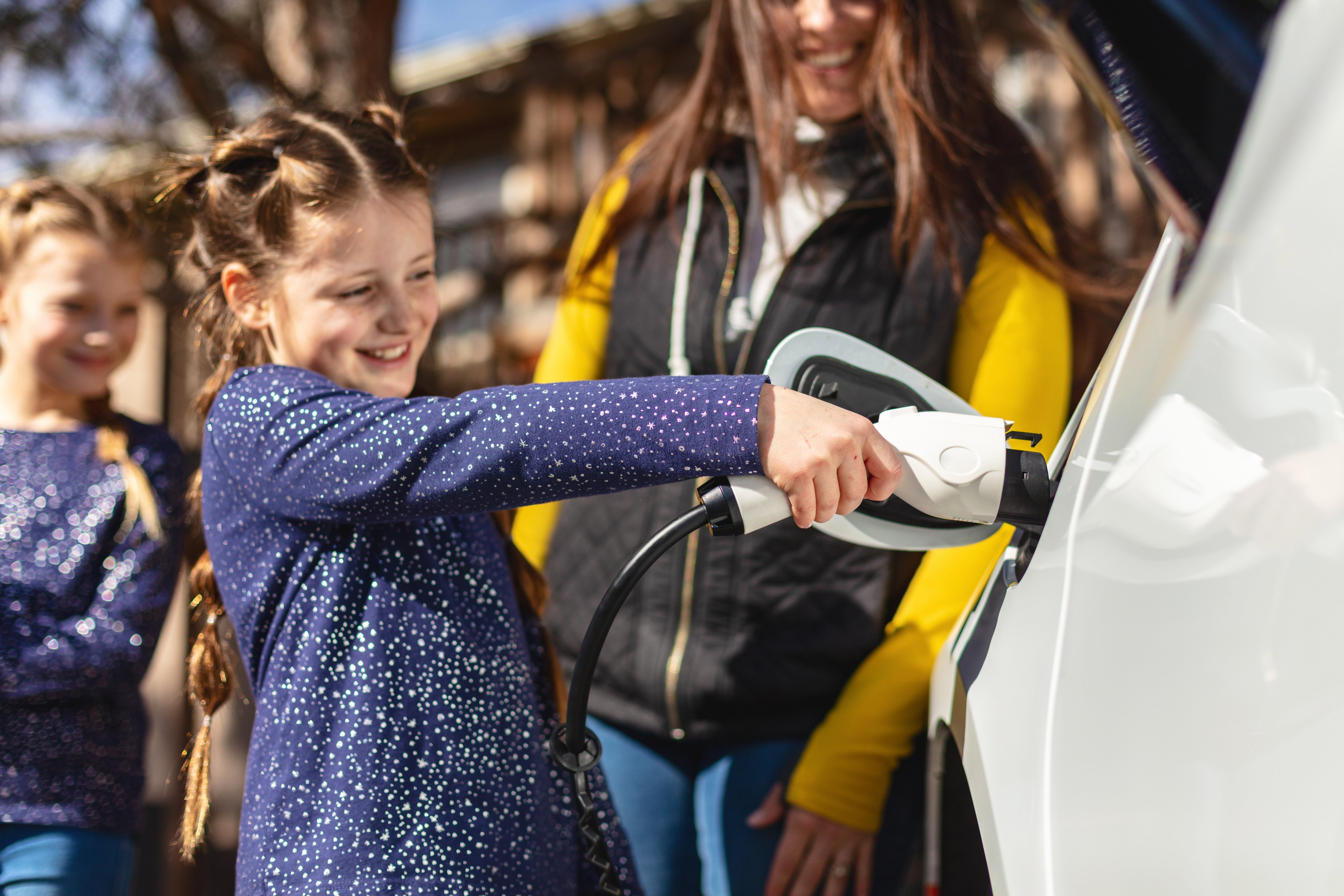 Family charging car while preparing for travel