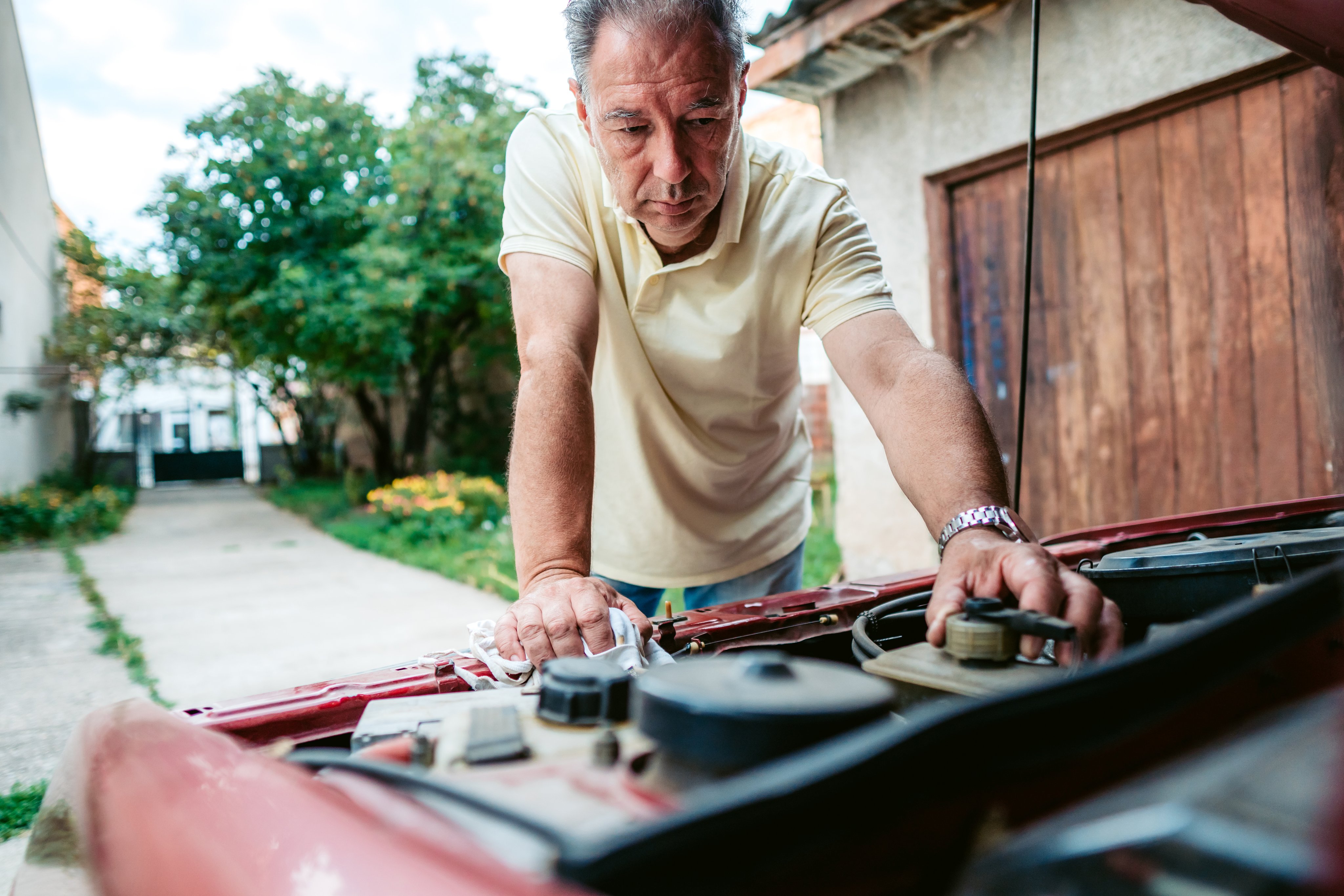 Senior man repairing car in his yard