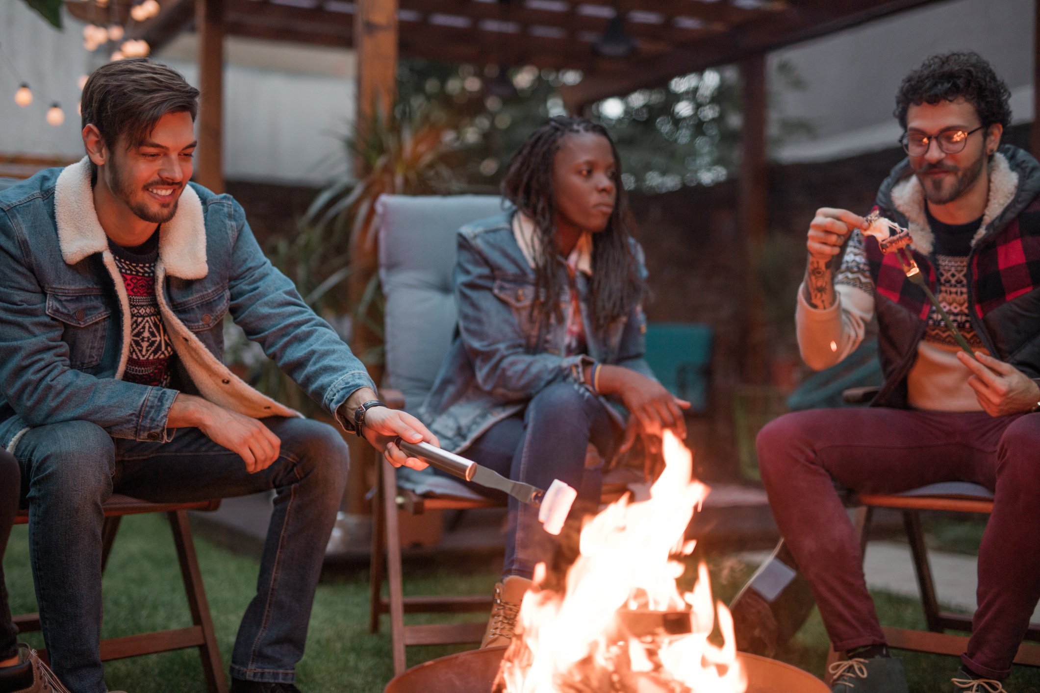 Friends roasting marshmallows over fire pit