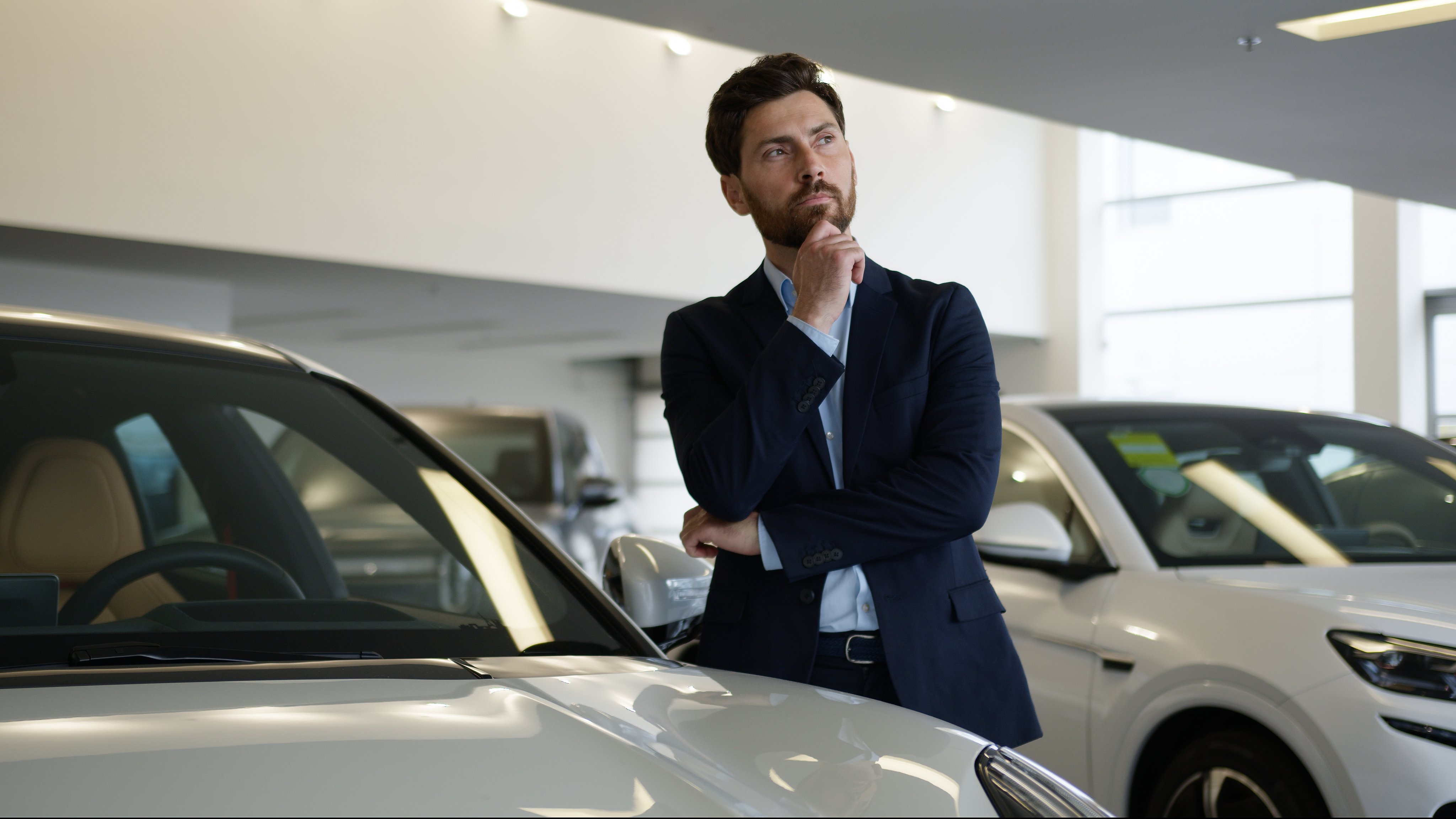 Thoughtful pensive Caucasian man client consumer new car choosing thinking decide purchase auto vehicle