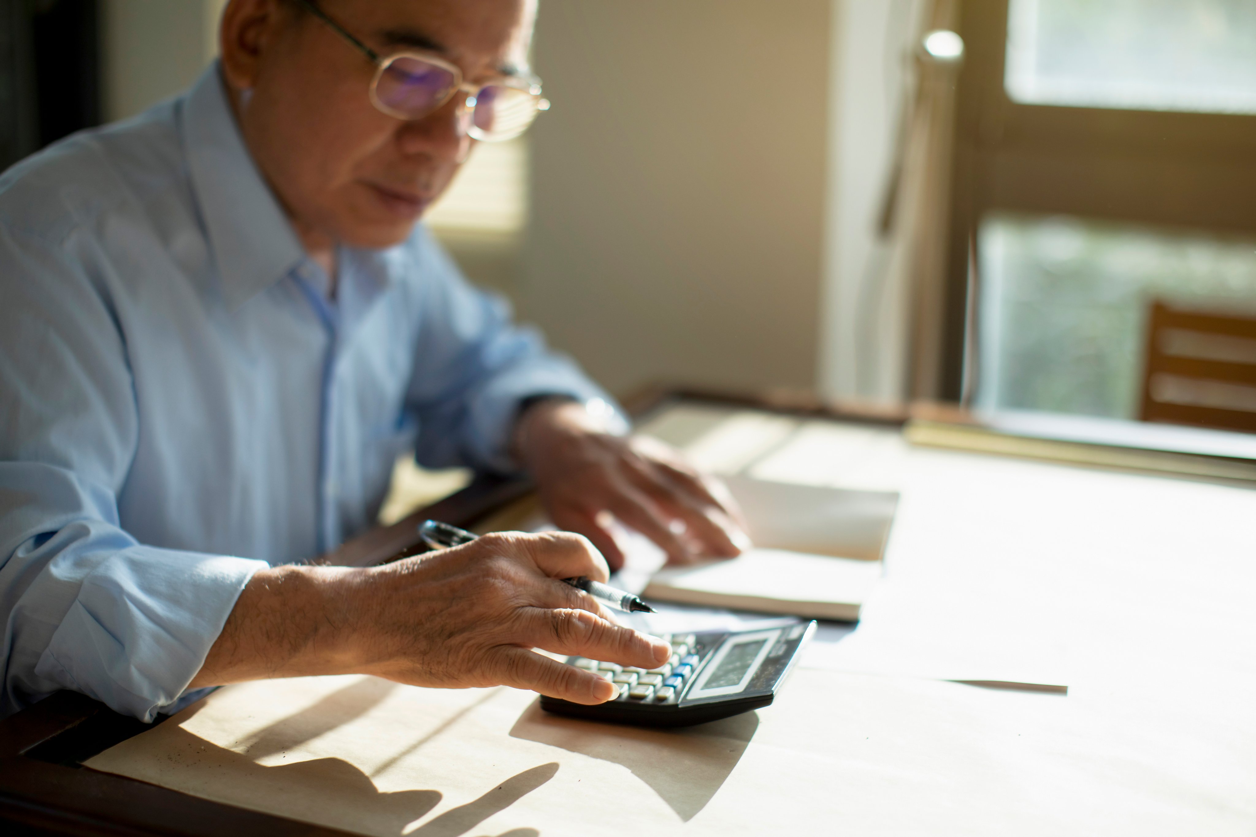 Senior man sitting at table and calculating finances