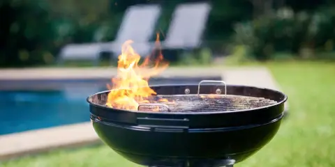 Charcoal grill with open flames burning in a backyard