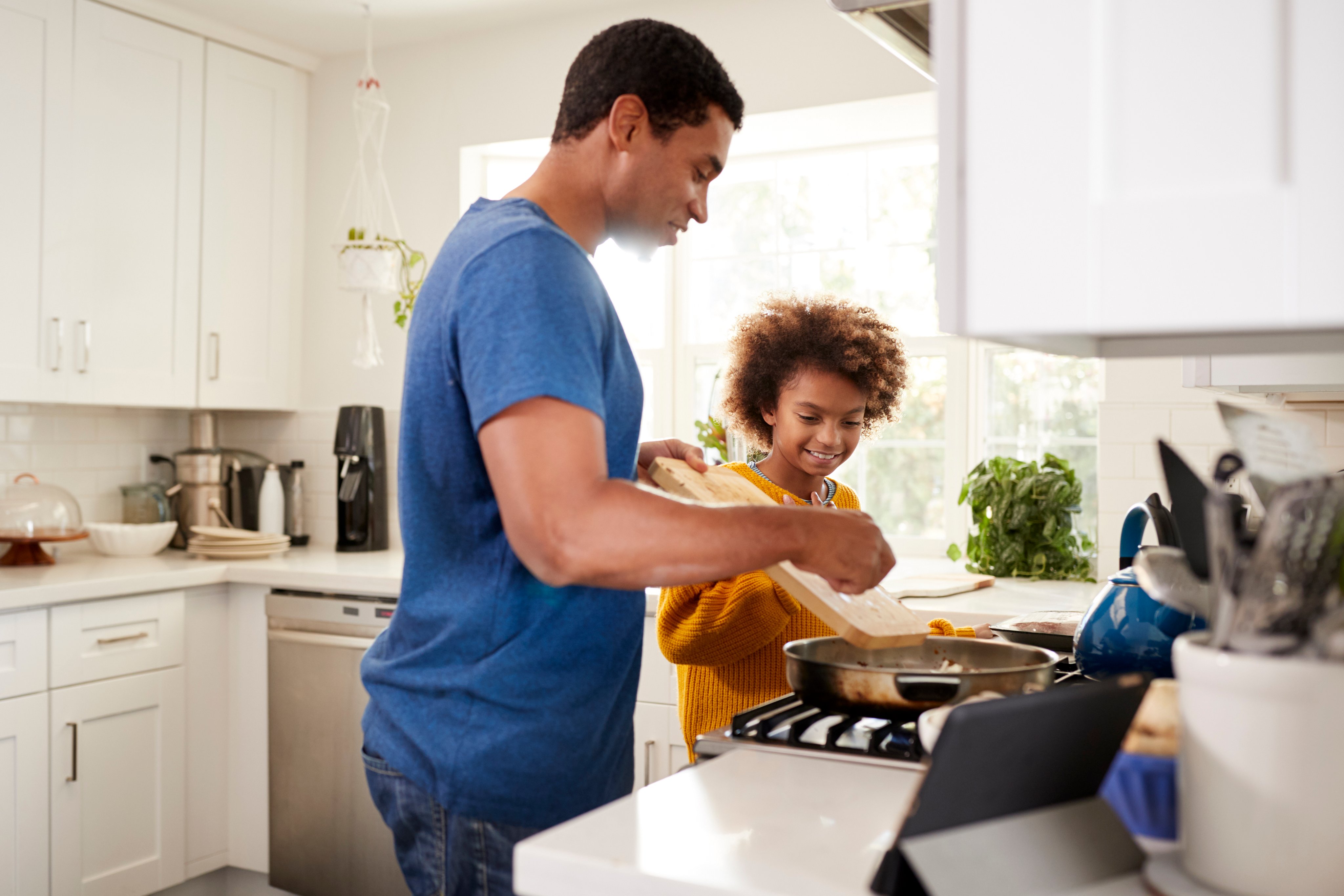 Father and daughter cooking food in kitchen