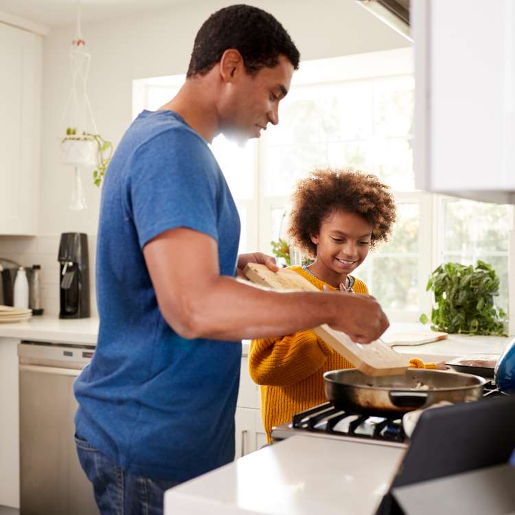 Father and daughter cooking food in kitchen