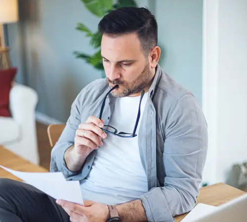 Male sitting in his office in front of a laptop, reading an insurance document