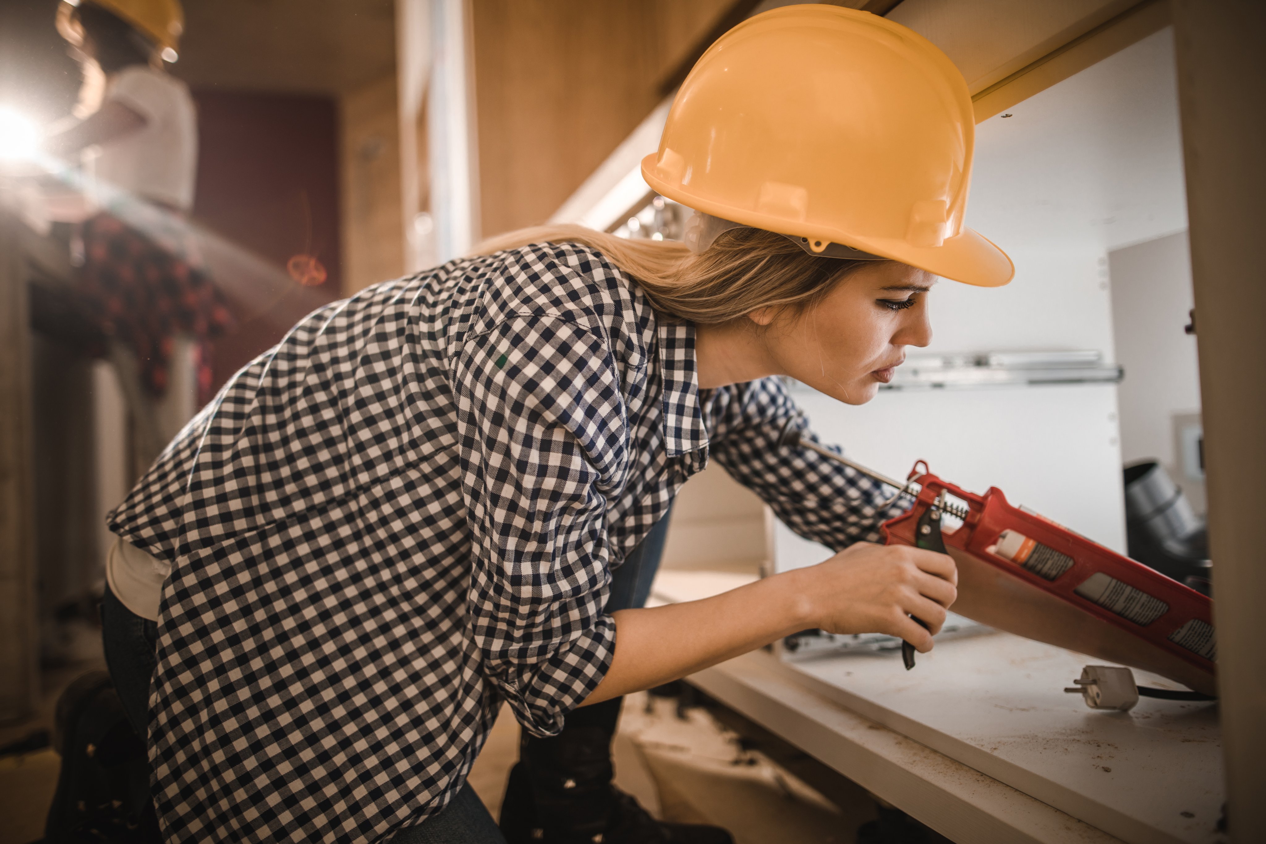 Woman caulking sink plumbing