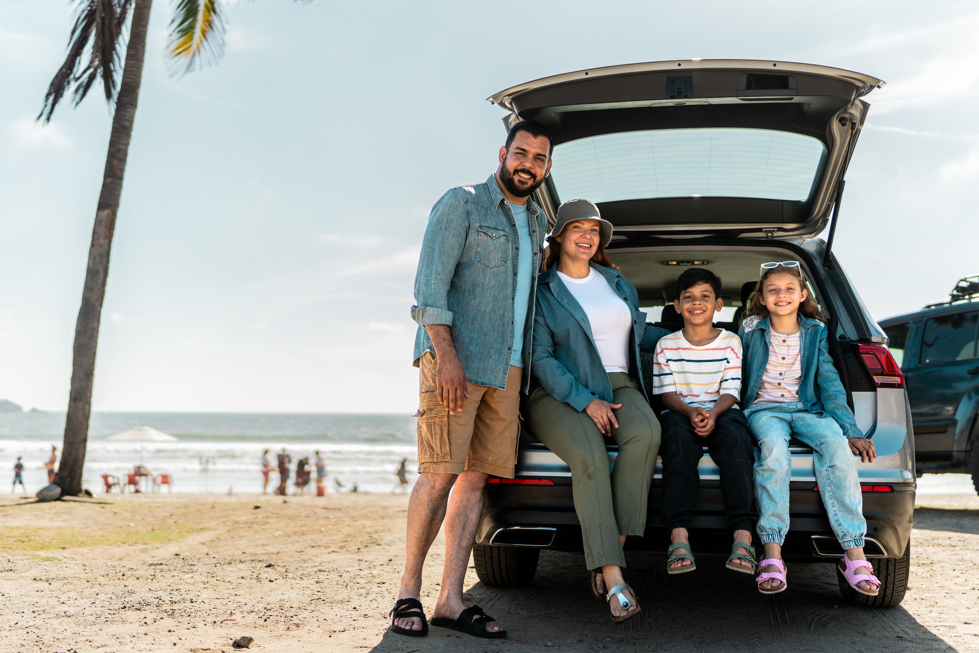 Family of four sitting in the back of a car on the beach