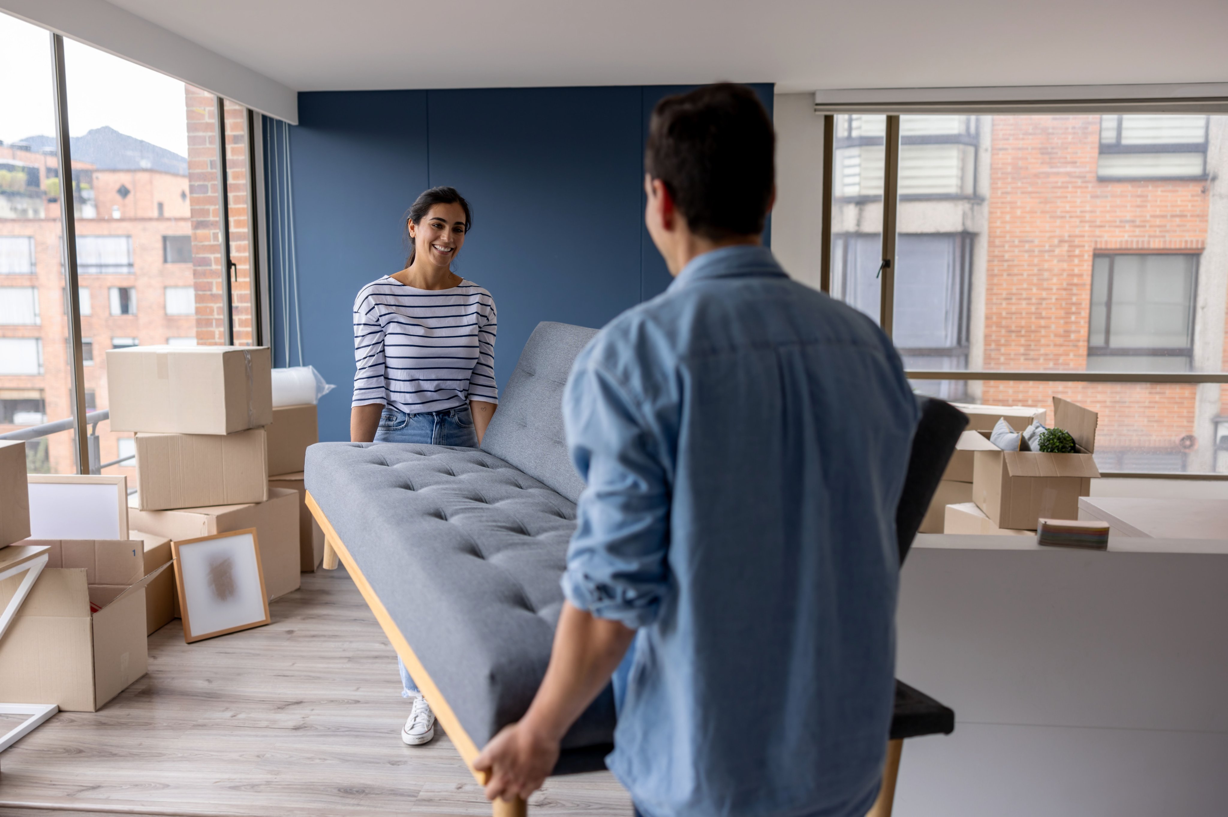 Smiling couple carrying a couch into their apartment