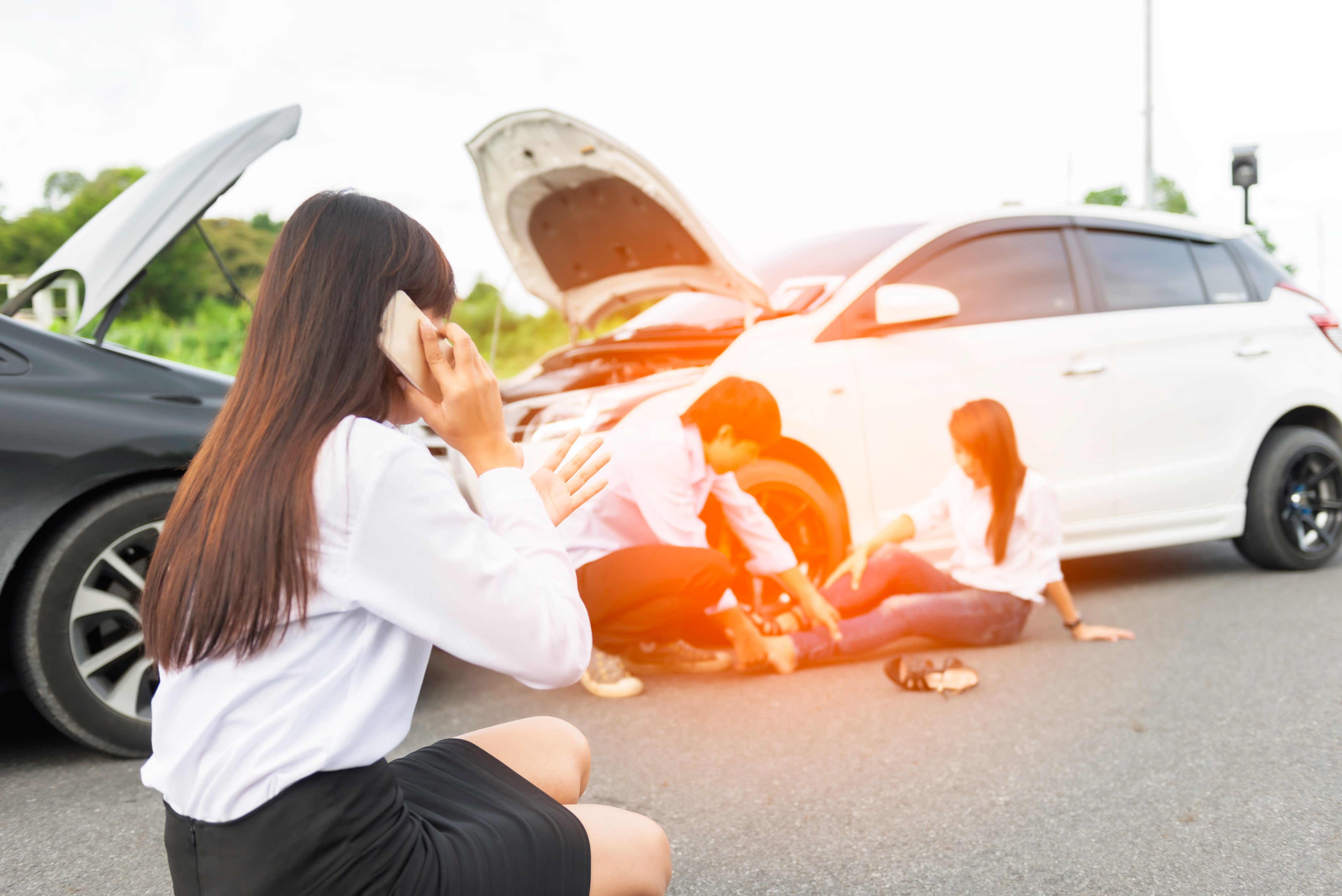 Young woman with smartphone by the damaged car after a car accident, making a phone call and for insurance agent to quick attention