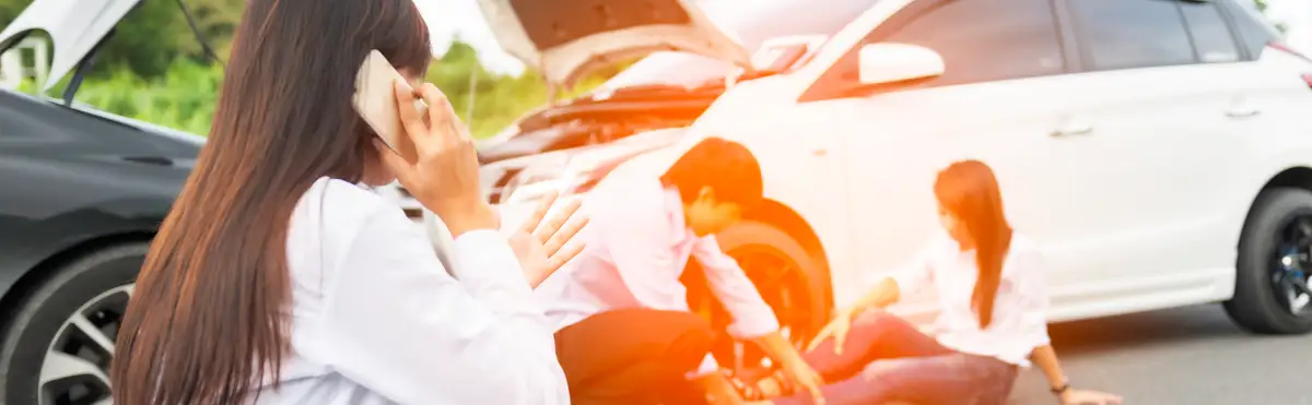 Young woman with smartphone by the damaged car after a car accident, making a phone call and for insurance agent to quick attention