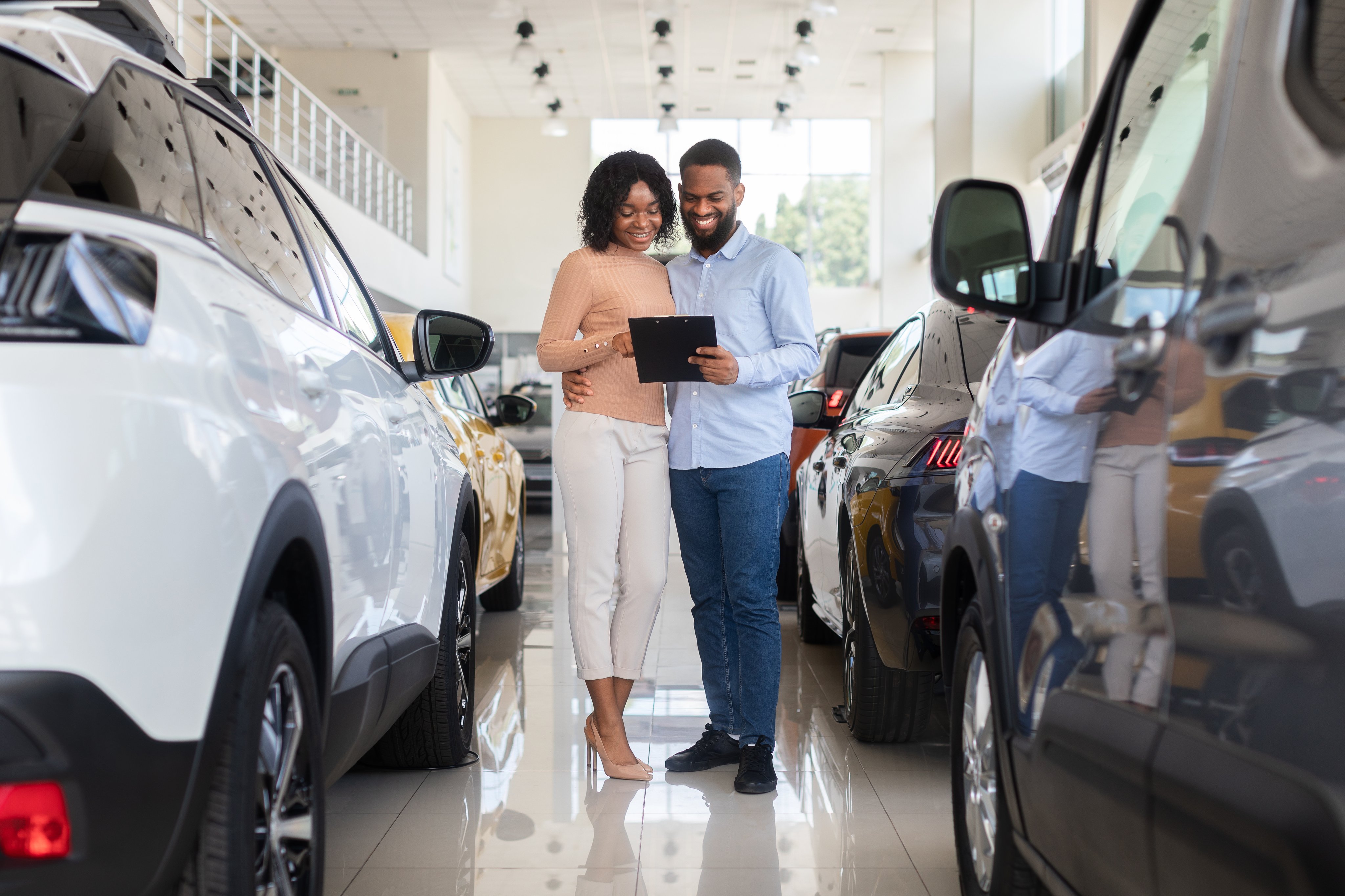Young black couple choosing car in modern dealership