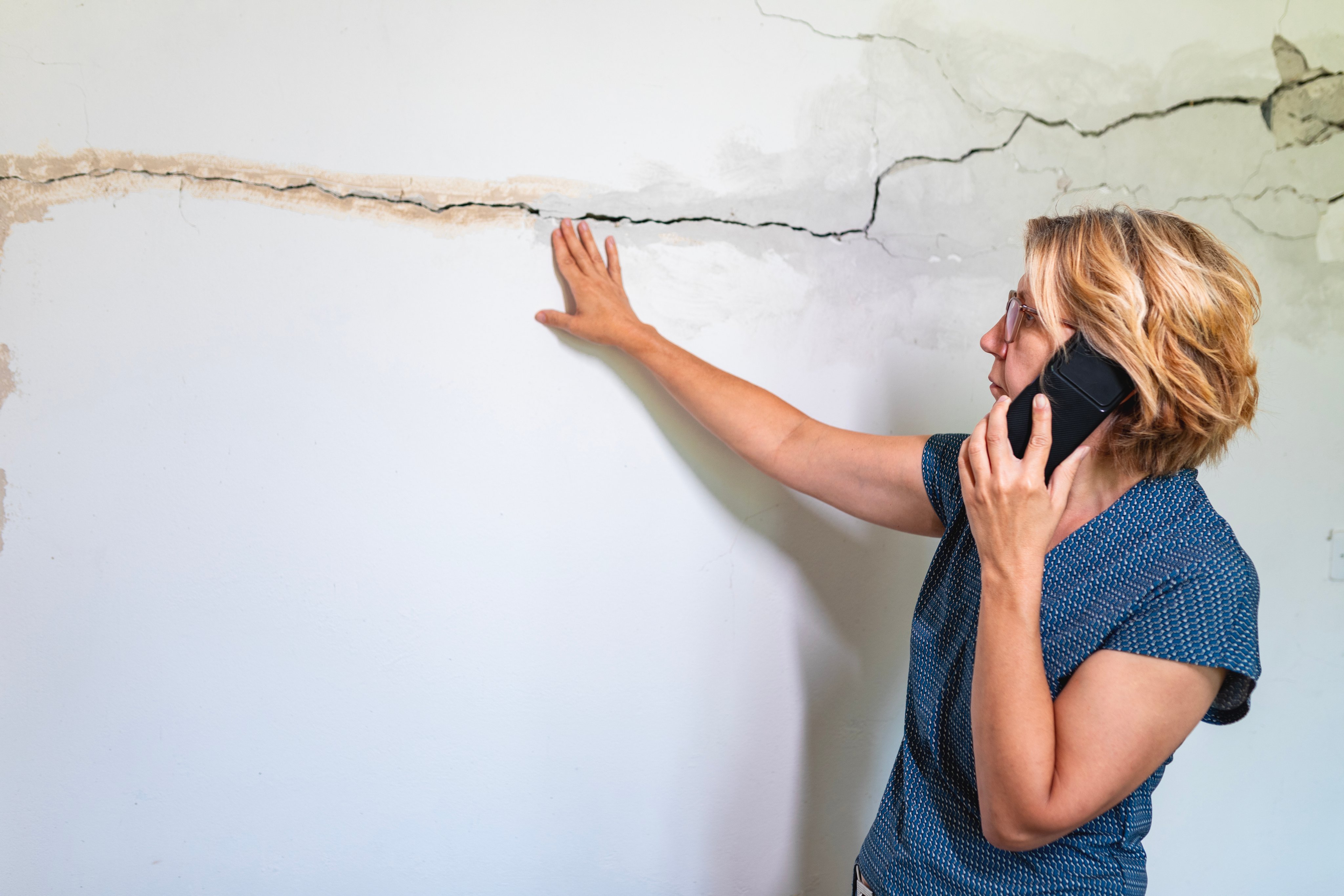 Woman looking at a wall damaged after the earthquake
