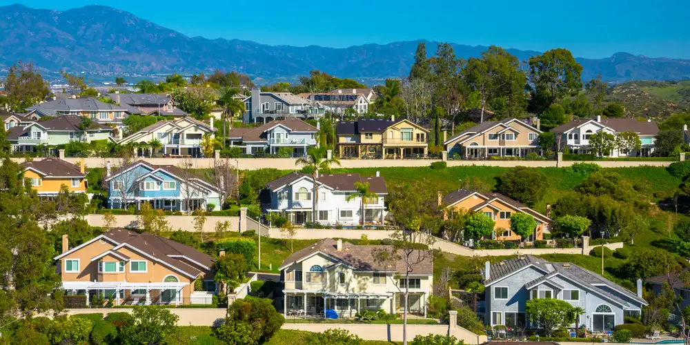 A hillside with many houses in Irvine in southern Orange County, California, with mountains in the background.