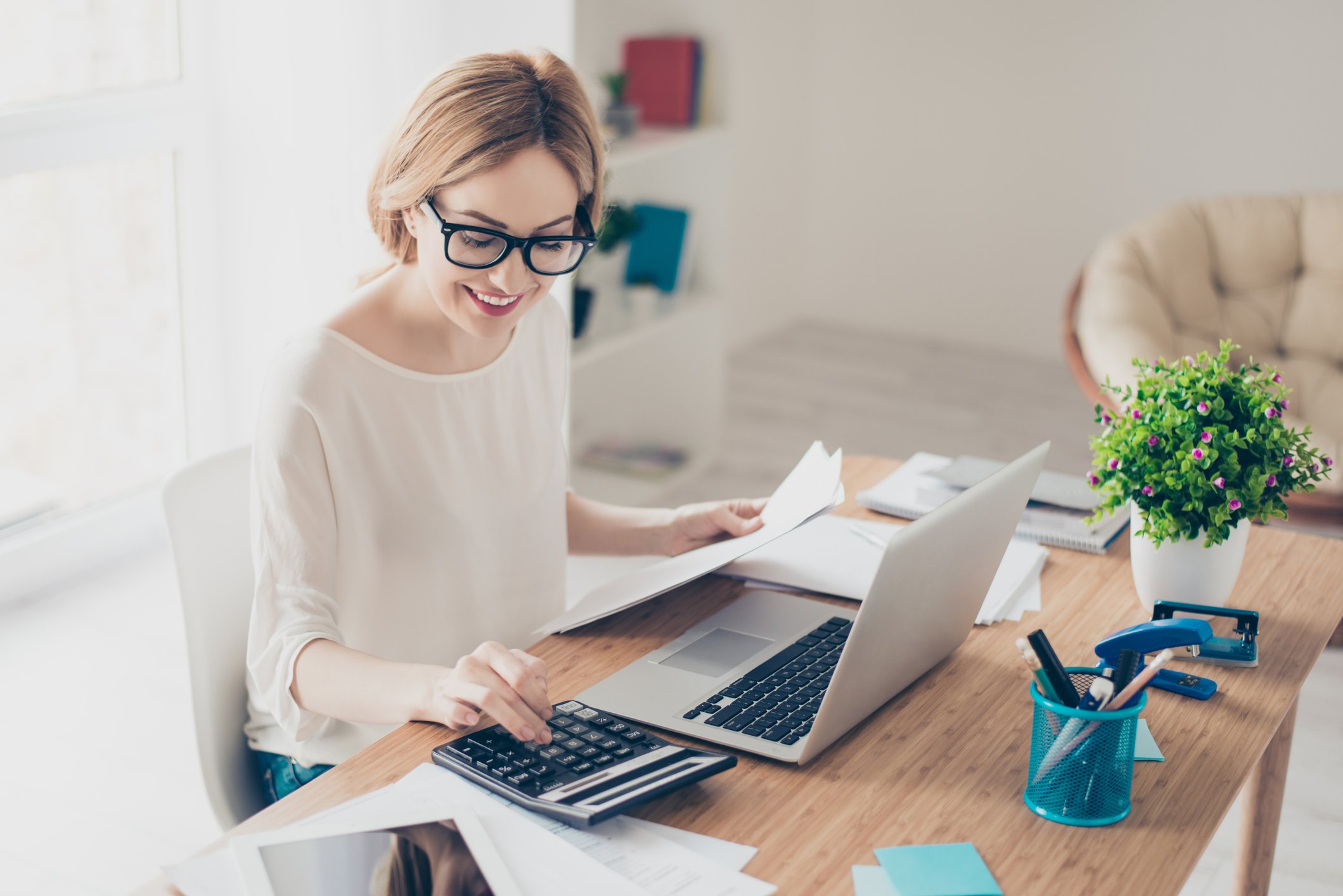 Happy woman working at computer and calculator