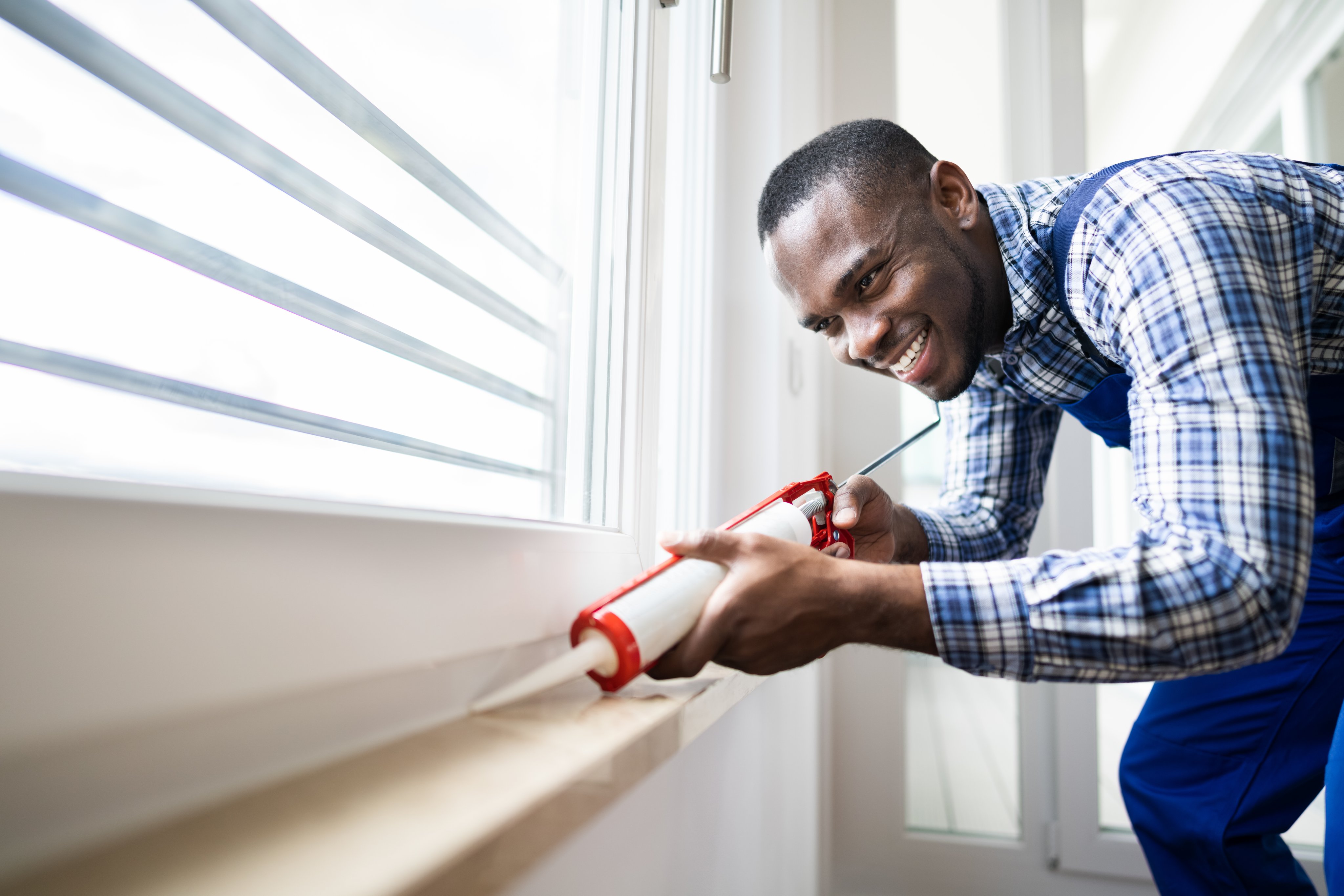 Homeowner applying a caulk sealant to window seal