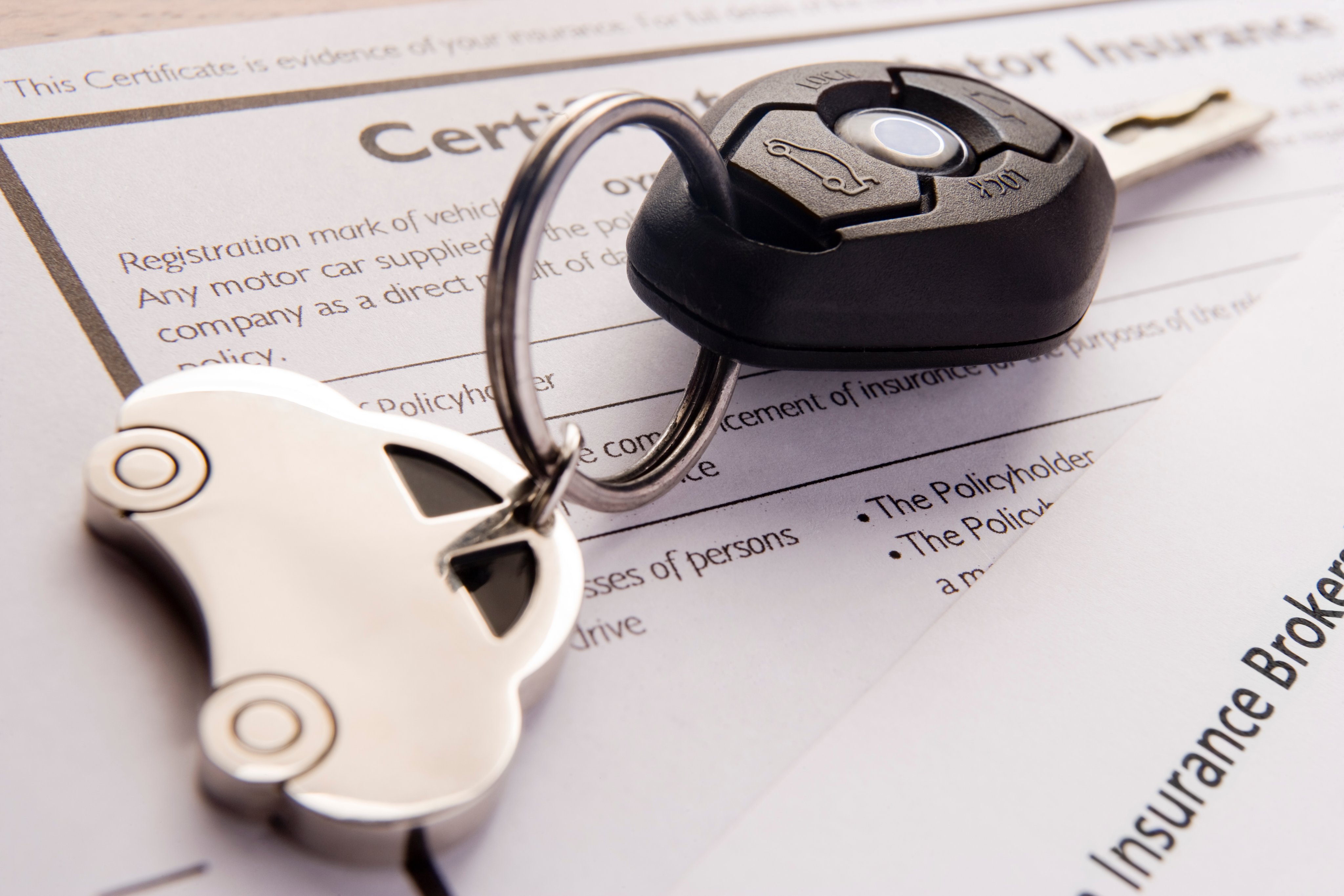 Car keys over sitting on top of car insurance papers