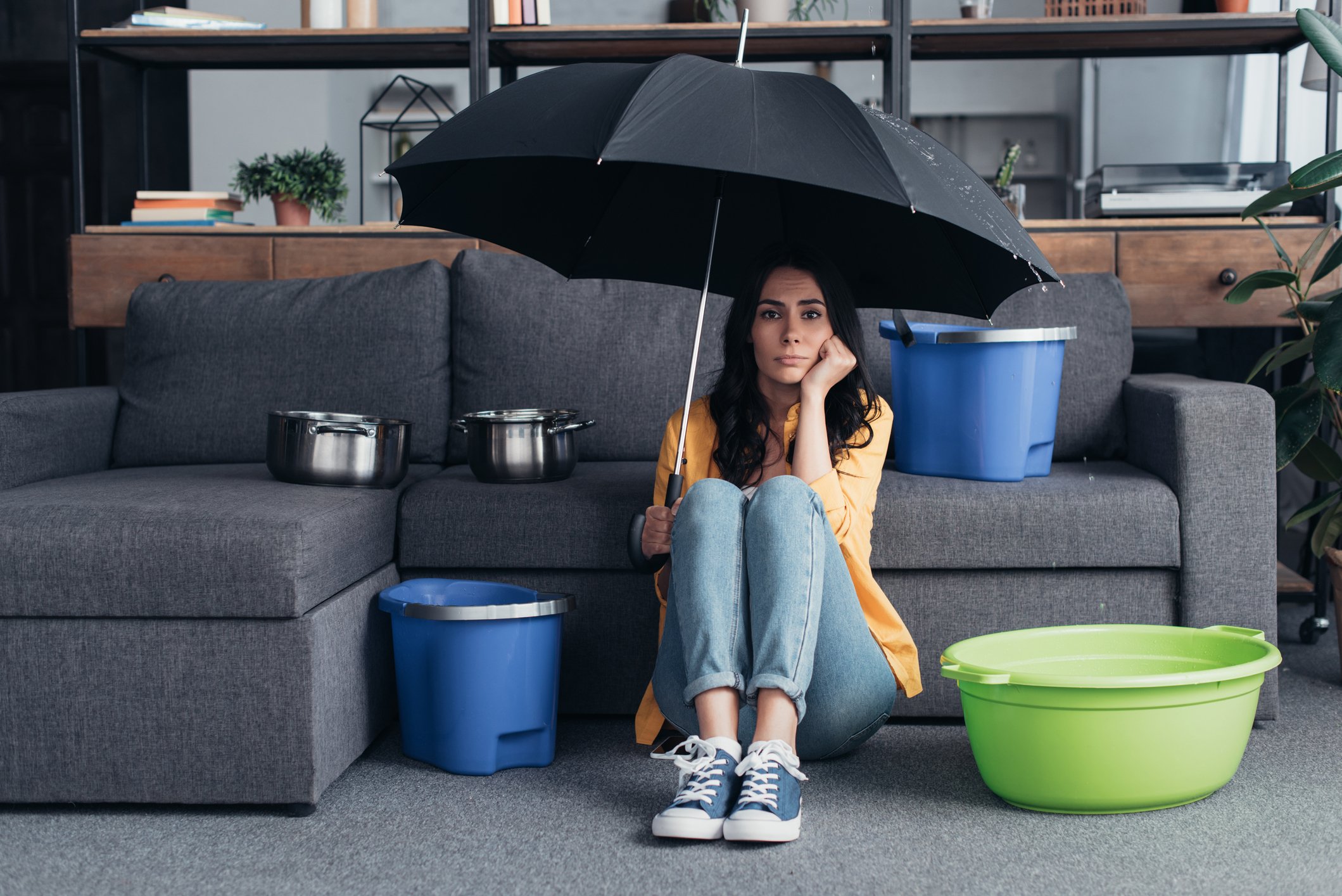 Pensive woman sitting on floor with umbrella