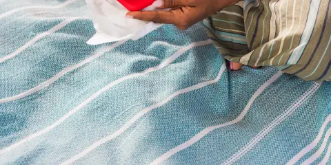 Woman's hands holding an open diaper with valuables on a sandy beach