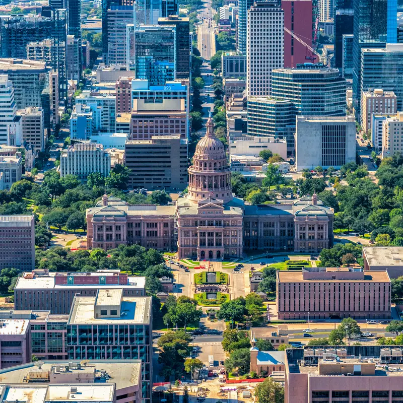 Aerial view of Texas State Capitol Building in the foreground with the skyline of Austin, Texas