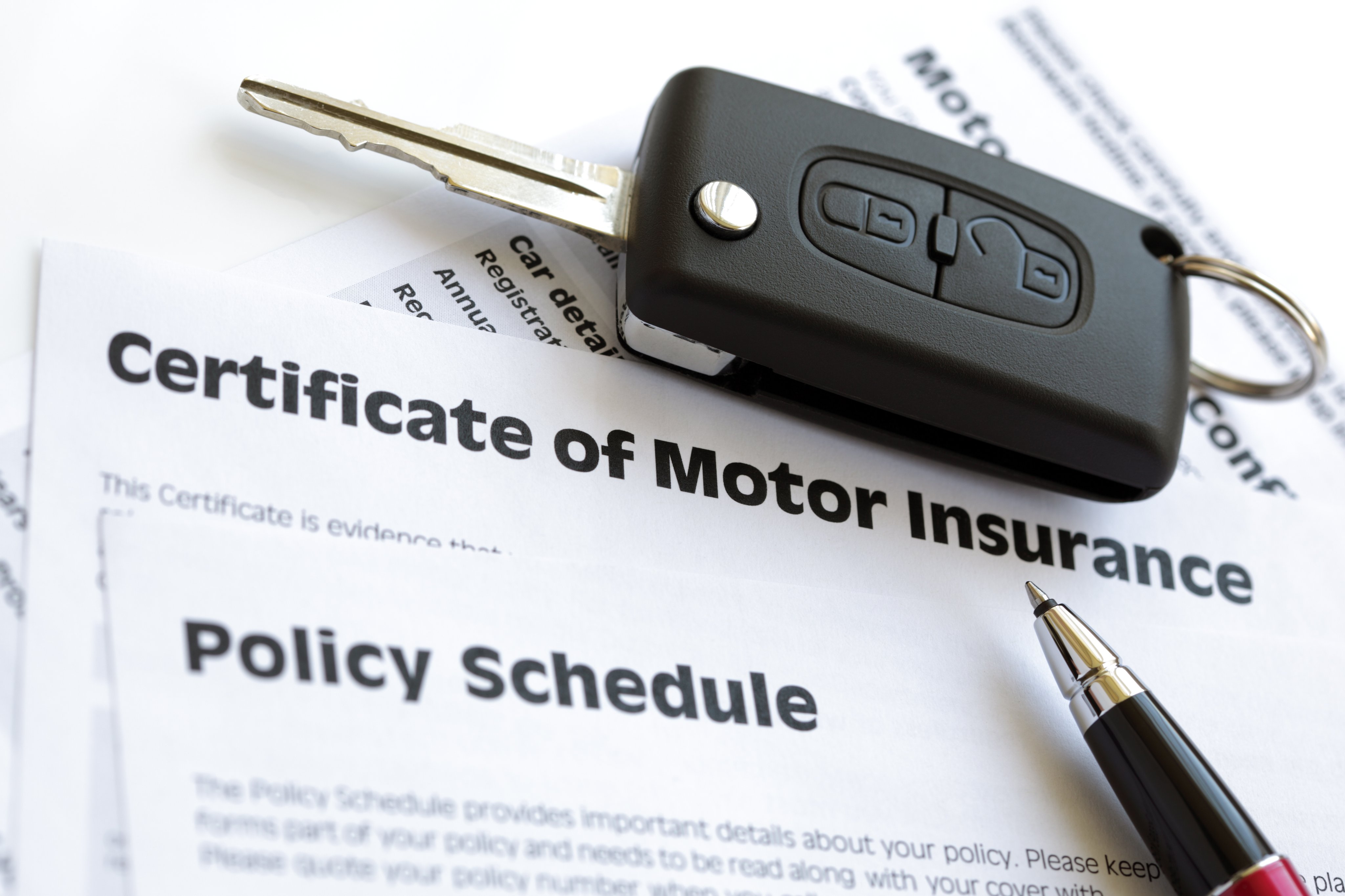 Car key on stack of insurance papers 