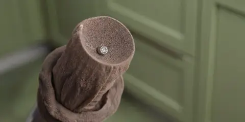 Close-up of a vacuum hose covered with pantyhose over the end, used as a filter while cleaning, with a small earring caught on the fabric