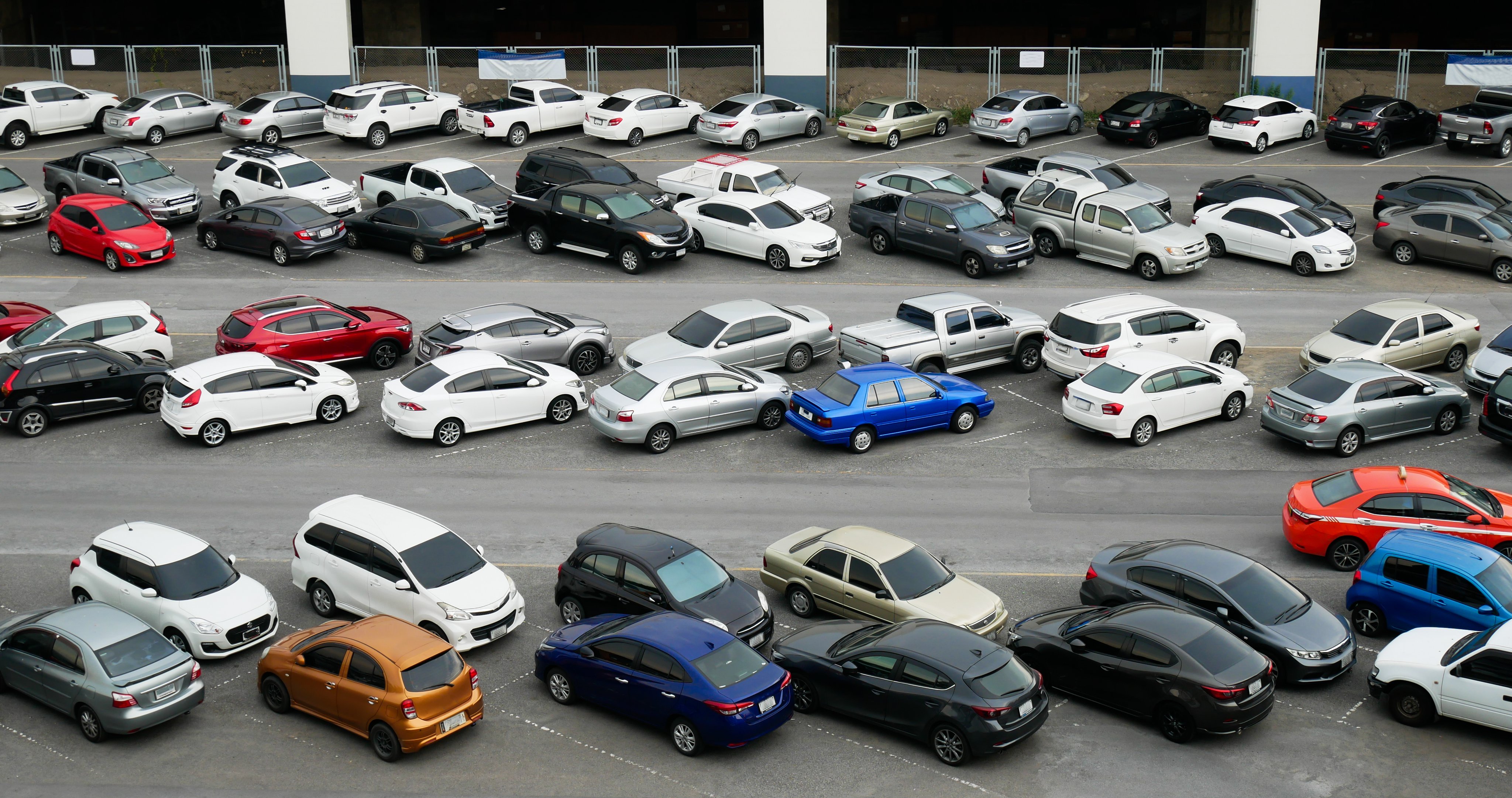 Cars parked in outdoor parking lot at with many of buildings in background.