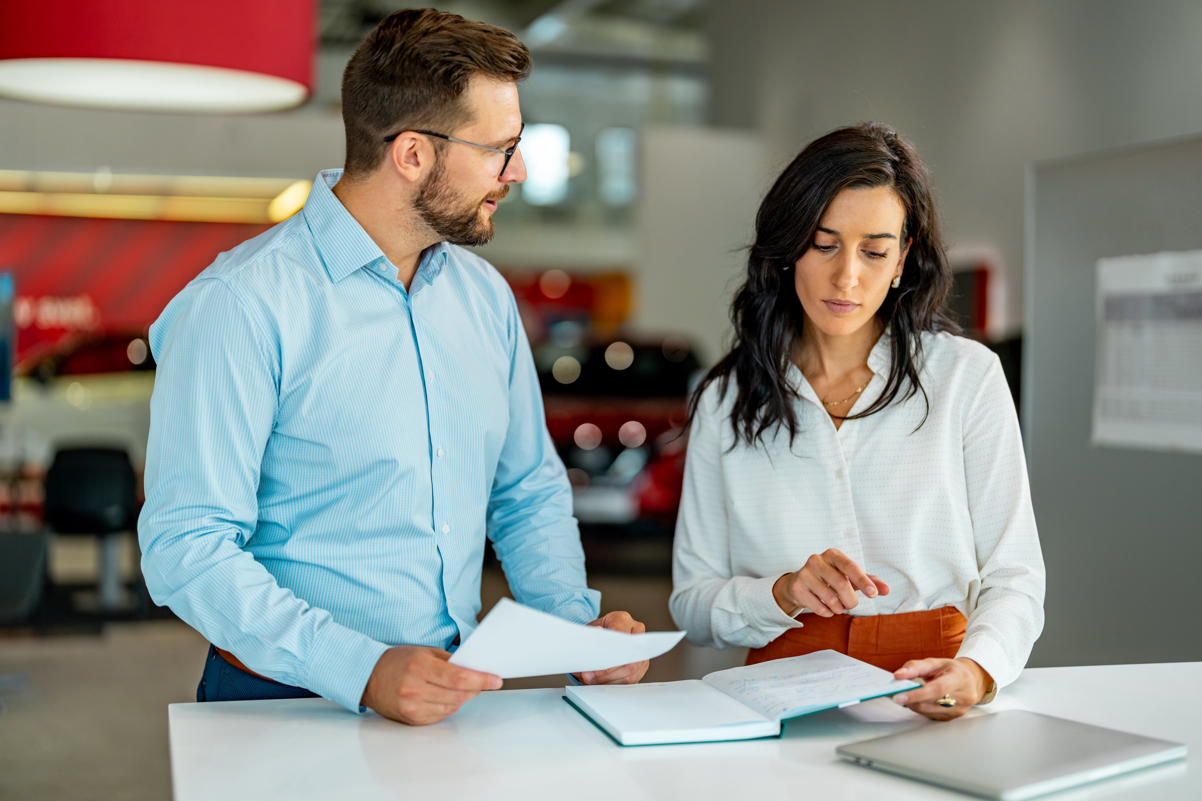 Shot of a car salesman going over paperwork with his customer