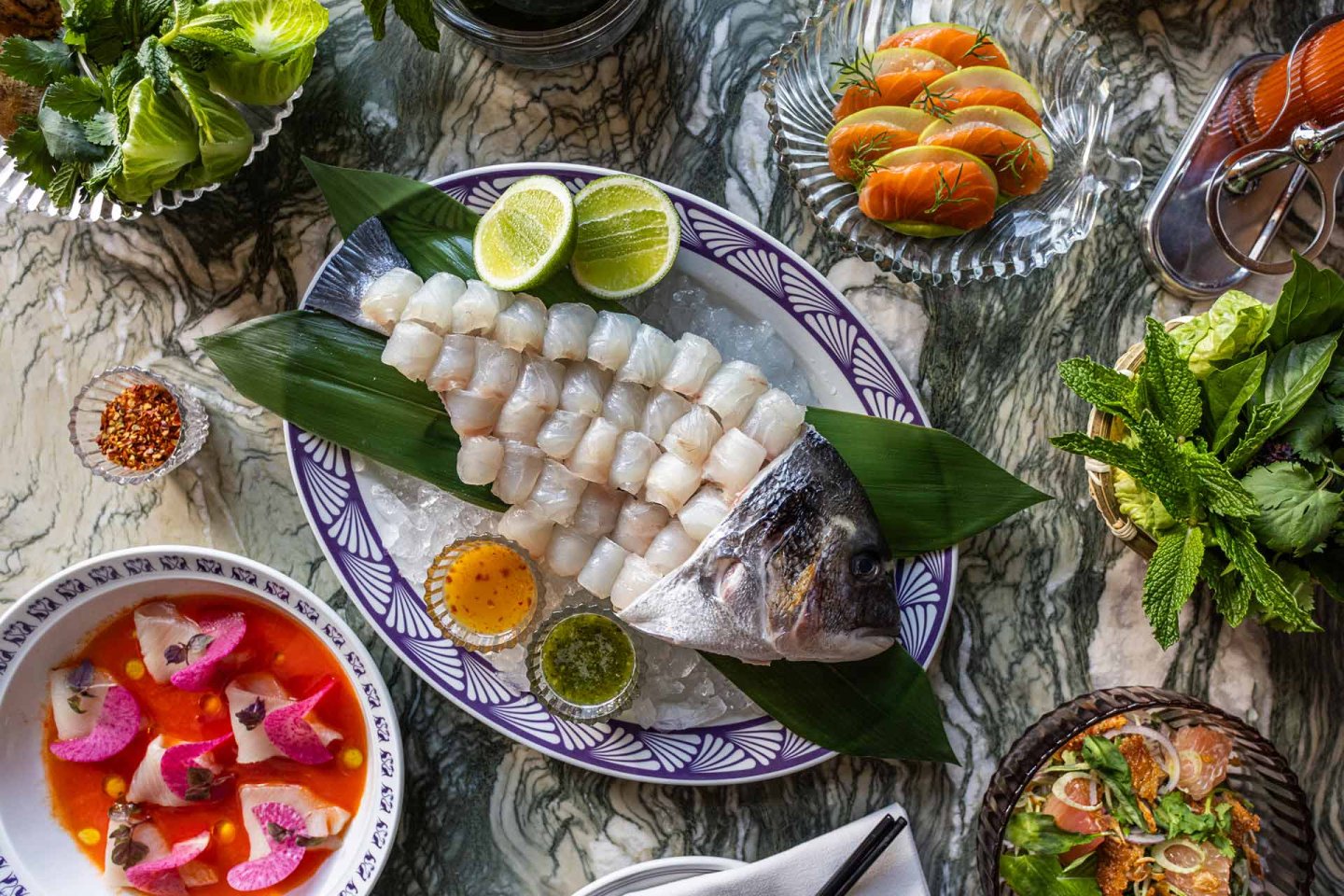 A plate of fish on a leaf with other food on it.