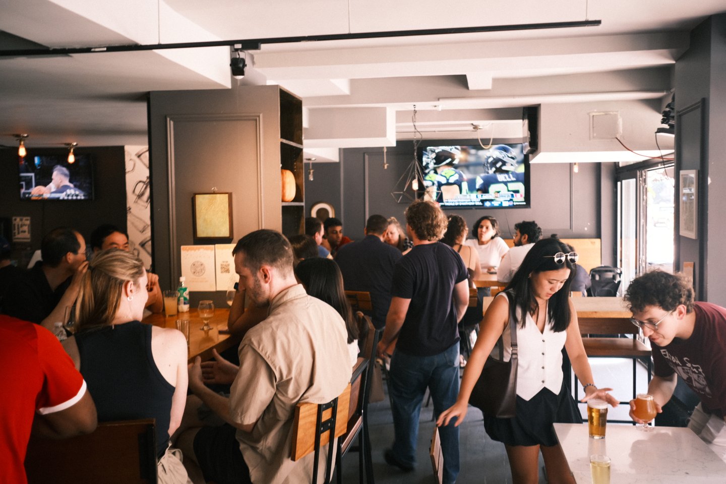 Guests gathered at Milk & Hops craft beer bar in Chelsea, Manhattan, watching a live soccer match while enjoying beer and game-day atmosphere.