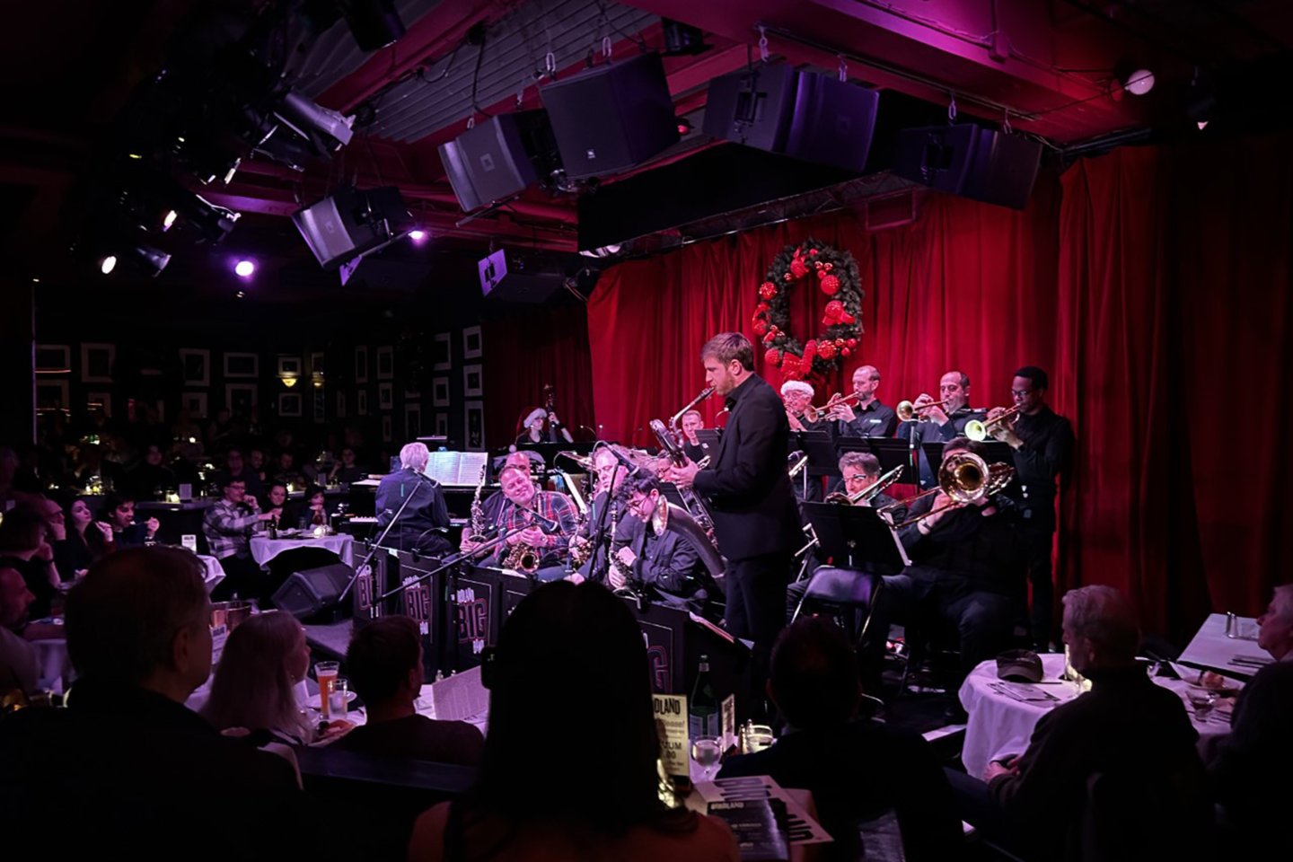 a band playing in a dark room with red curtains.