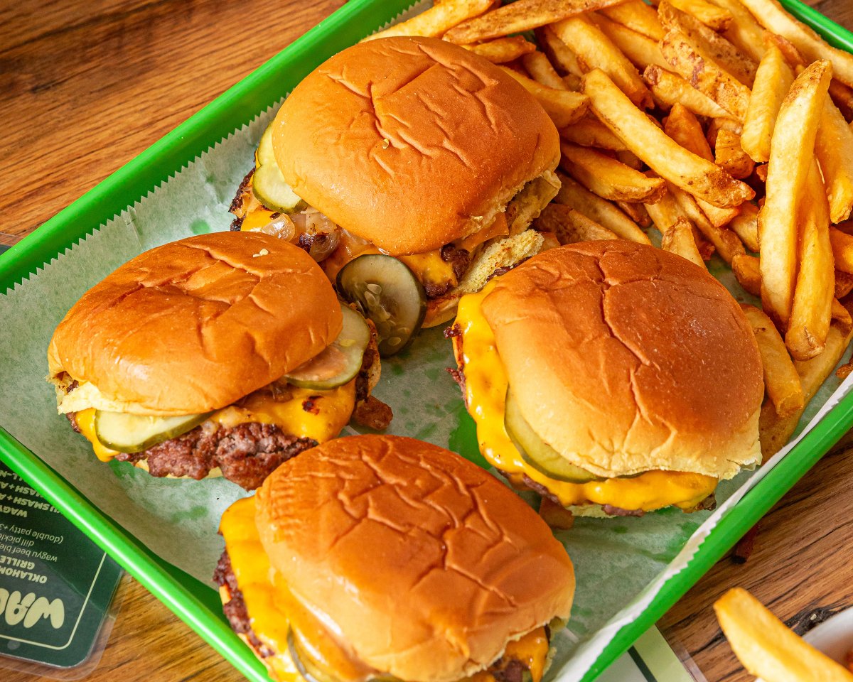 Four 4oz 30-day dry-aged smash burgers on a green tray surrounded by all-natural french fries from Bareburger, selling for $26 to celebrate the 2026 World Cup in New York City & New Jersey