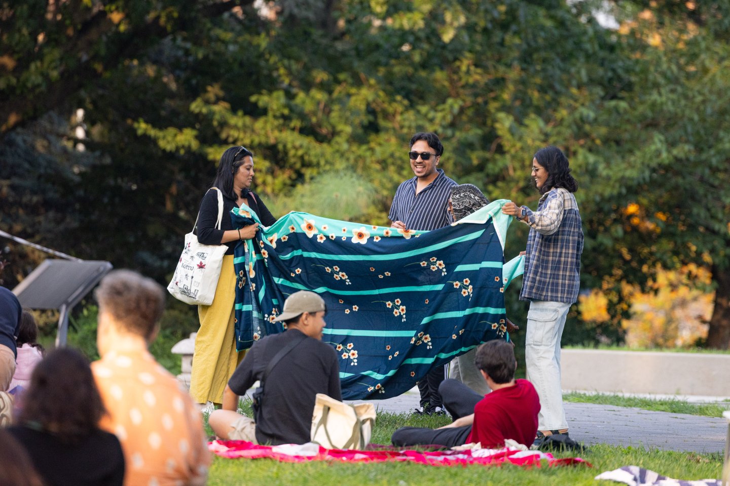 A group of people set up a picnic for an outdoor screening at Queens Botanical Garden